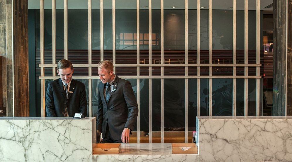 Two members of staff at a White Lodging hotel reception desk.